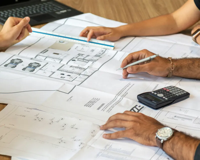 Two people working over architectural drawings for the next project