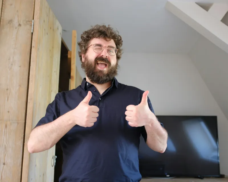 A delighted homeowner giving two thumbs up in a newly finished room